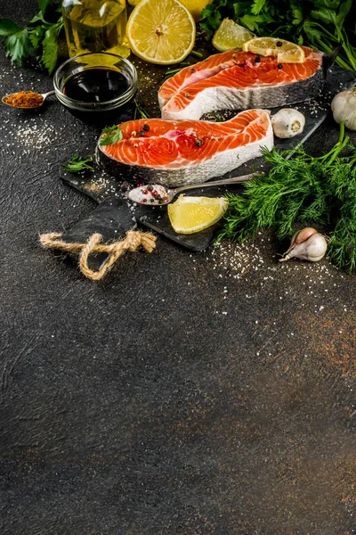 Çiğ Somon Balık biftek ile limon, otlar, zeytin yağı, ızgara, kayrak kesme tahtası, karanlık paslı arka plan kopya alanı için hazır