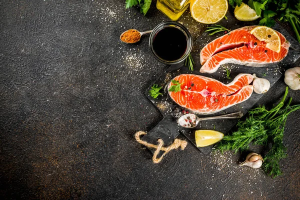 Çiğ Somon Balık biftek ile limon, otlar, zeytin yağı, ızgara, kayrak kesme tahtası, karanlık paslı arka plan kopya alanı için hazır