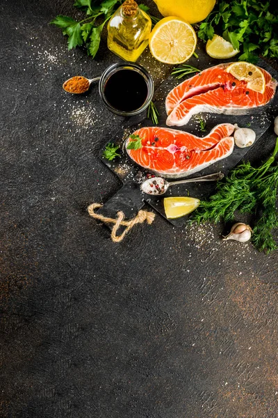 Çiğ Somon Balık biftek ile limon, otlar, zeytin yağı, ızgara, kayrak kesme tahtası, karanlık paslı arka plan kopya alanı için hazır