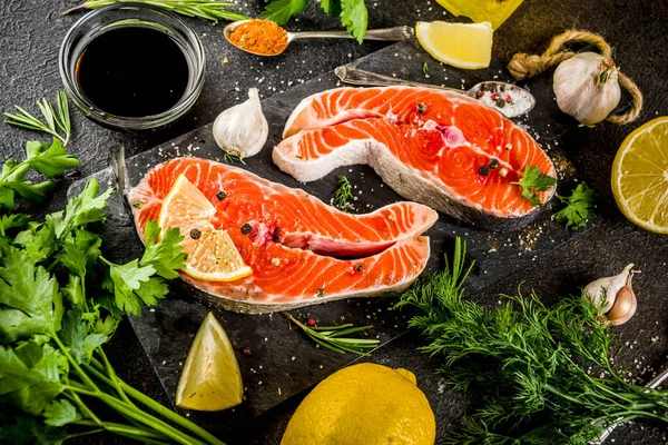Çiğ Somon Balık biftek ile limon, otlar, zeytin yağı, ızgara, kayrak kesme tahtası, karanlık paslı arka plan kopya alanı için hazır