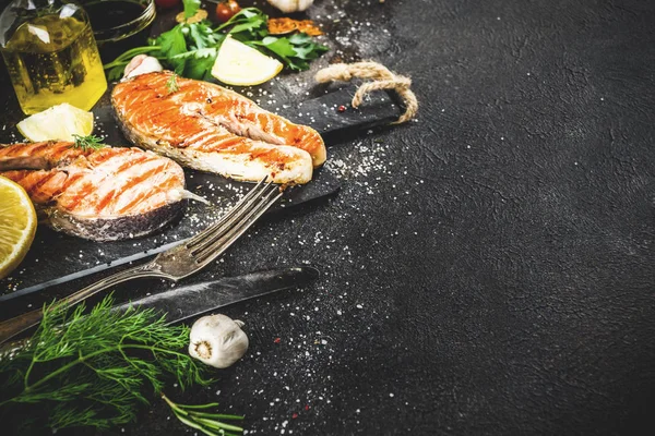 Izgara Somon Balık biftek malzemeler limon, otlar, zeytin yağı, kayrak kesme tahtası, karanlık paslı arka plan kopya alanı ile