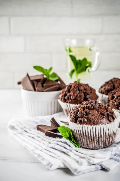 Home baked mint and chocolate muffins with mint tea, white marble background copy space