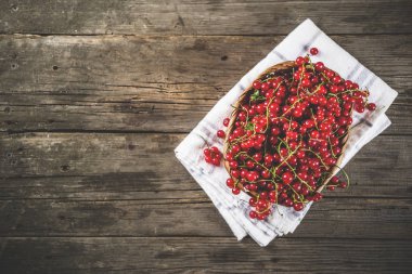 Küçük sepet, rustik ahşap masa kopya alanı içinde kırmızı kuş üzümü