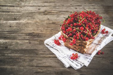 Küçük sepet, rustik ahşap masa kopya alanı içinde kırmızı kuş üzümü