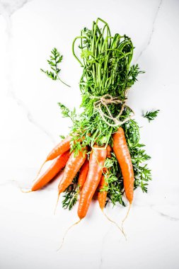 Yeşil yaprakları, beyaz mermer arka plan ile taze çiğ havuç alan en iyi görünüm Kopyala