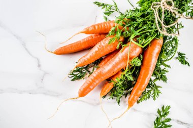Yeşil yaprakları, beyaz mermer arka plan ile taze çiğ havuç alan en iyi görünüm Kopyala