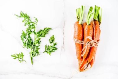 Yeşil yaprakları, beyaz mermer arka plan ile taze çiğ havuç alan en iyi görünüm Kopyala