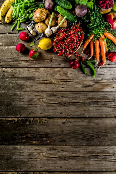 Fresh summer fruit, berry and vegetables on wooden rustic background copy space above