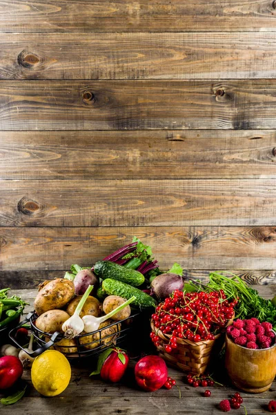 Fresh summer fruit, berry and vegetables on wooden rustic background copy space above