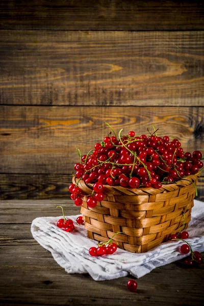 Küçük sepet, rustik ahşap masa kopya alanı içinde kırmızı kuş üzümü