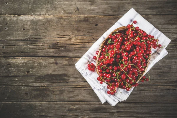 Küçük sepet, rustik ahşap masa kopya alanı içinde kırmızı kuş üzümü