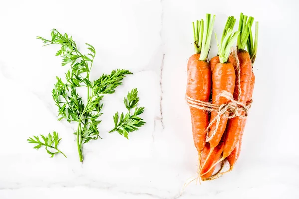 Yeşil yaprakları, beyaz mermer arka plan ile taze çiğ havuç alan en iyi görünüm Kopyala