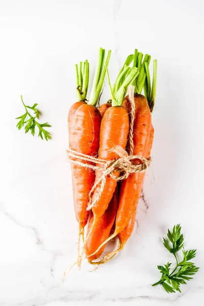 Yeşil yaprakları, beyaz mermer arka plan ile taze çiğ havuç alan en iyi görünüm Kopyala