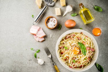 Geleneksel İtalyan Makarna, spagetti carbonara pastırma, krem sos, parmesan peyniri, yumurta sarısı ve taze fesleğen yaprakları gri taş arka plan kopya alanı