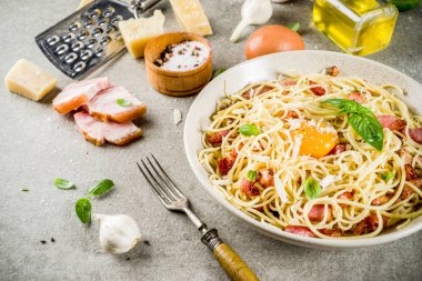 Geleneksel İtalyan Makarna, spagetti carbonara pastırma, krem sos, parmesan peyniri, yumurta sarısı ve taze fesleğen yaprakları gri taş arka plan kopya alanı