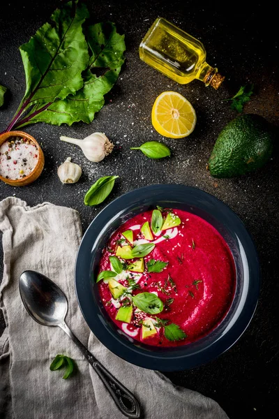 Vegan food, summer cold Beetroot gazpacho soup with lemon, avocado and fresh herbs copy space top view