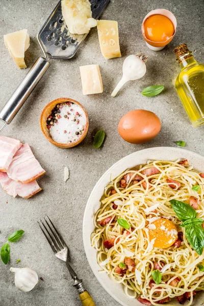 Geleneksel İtalyan Makarna, spagetti carbonara pastırma, krem sos, parmesan peyniri, yumurta sarısı ve taze fesleğen yaprakları gri taş arka plan kopya alanı