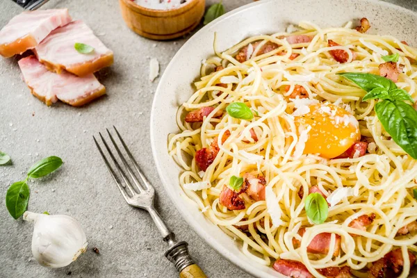 Geleneksel İtalyan Makarna, spagetti carbonara pastırma, krem sos, parmesan peyniri, yumurta sarısı ve taze fesleğen yaprakları gri taş arka plan kopya alanı