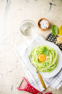Trendy vegan yemek tarifleri, peynirli kabak spagetti makarna ile yumurta sarısı parmesan, zeytin yağı ve fesleğen yaprakları, hafif beton arka plan kopya alanı