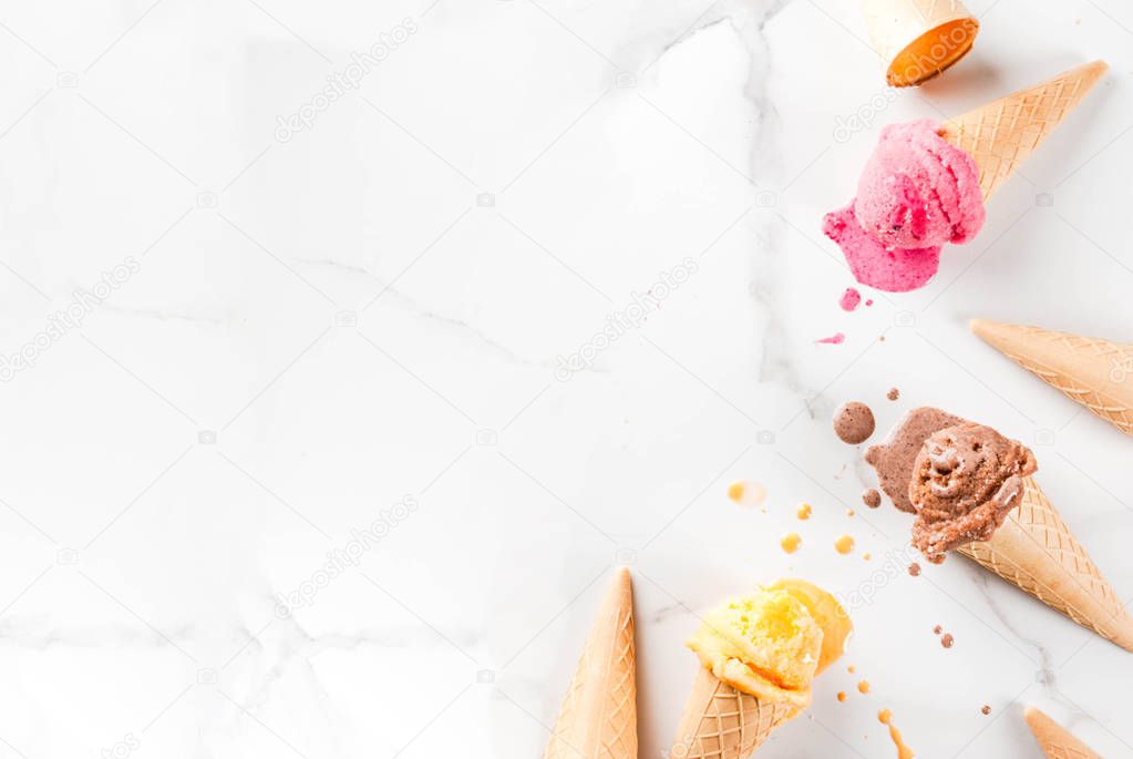 Homemade chocolate, vanilla, berry ice cream in ice cream cones, white marble background copy space top view