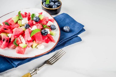 Yaz gıda kavramı, beyaz peynir, yaban mersini, avokado ve nane, beyaz mermer zemin kopya alanı ile taze soğuk karpuz salatası
