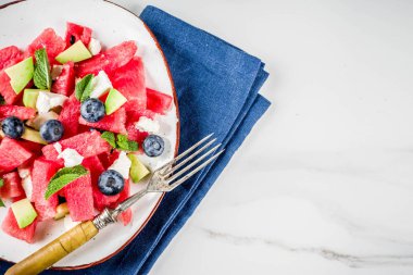 Yaz gıda kavramı, beyaz peynir, yaban mersini, avokado ve nane, beyaz mermer zemin kopya alanı ile taze soğuk karpuz salatası