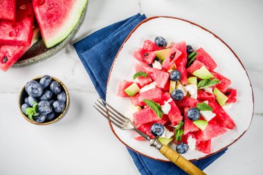 Yaz gıda kavramı, beyaz peynir, yaban mersini, avokado ve nane, beyaz mermer zemin kopya alanı ile taze soğuk karpuz salatası