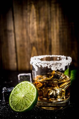 İki tekila shot bardağı buz küpleriyle koyu arka plan üzerine tuz ve limes alanı Kopyala