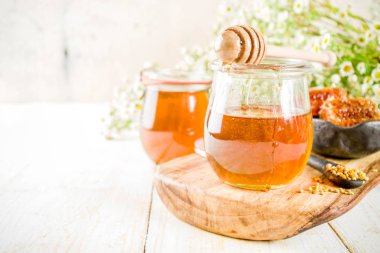 Organik çiçek bal, kavanoz, bir masada Beyaz ahşap, kır çiçekleri, polen ve bal tarak ile kopyalama alanı