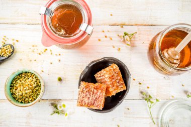 Organik çiçek bal, kavanoz, bir masada Beyaz ahşap, kır çiçekleri, polen ve bal tarak ile kopyalama alanı üstten görünüm