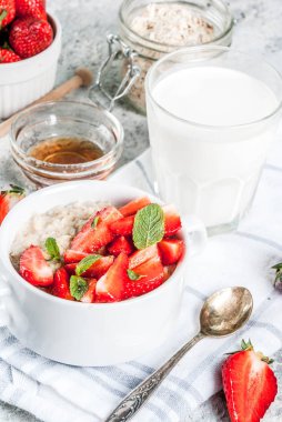 Sağlıklı yaz Kahvaltı, gece yulaf ezmesi taze çilek ve süt, gri taş arka plan