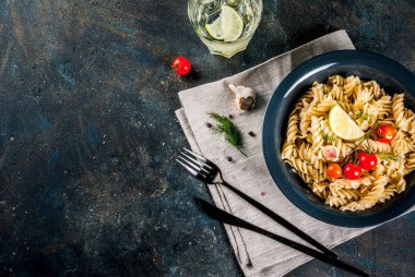 Klasik İtalyan makarna düdük pesto sos, domates, limon ve karanlık kapta taze otlar ile koyu mavi arka plan kopya alanı Üstten Görünüm