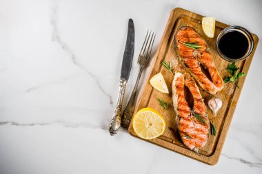 Izgara Somon Balık biftek malzemeler limon, otlar, zeytin yağı, kayrak kesme tahtası, karanlık paslı arka plan kopya alanı ile