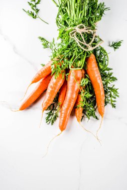 Yeşil yaprakları, beyaz mermer arka plan ile taze çiğ havuç alan en iyi görünüm Kopyala