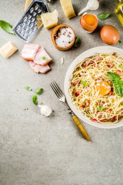Geleneksel İtalyan Makarna, spagetti carbonara pastırma, krem sos, parmesan peyniri, yumurta sarısı ve taze fesleğen yaprakları gri taş arka plan kopya alanı