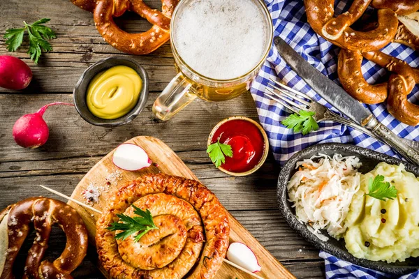 Oktoberfest food menu, bavarian sausages with pretzels, mashed potato, sauerkraut, beer bottle and mug old rustic wooden background, copy space above