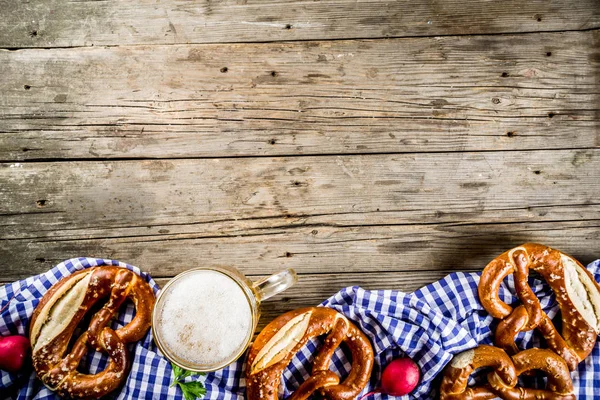 Oktoberfest food menu, bavarian pretzels with beer mug, old rustic wooden background, copy space above