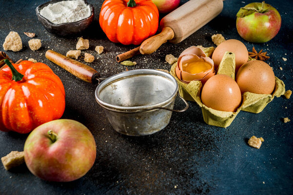 Sweet autumn baking cooking background with flour, rolling pin, decorative pumpkins, apples, cinnamon spices with anise cardamom sugar. Dark blue rusty background top view copy space