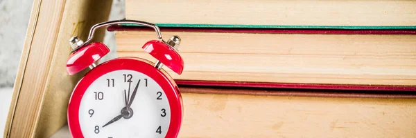 Back to school background with old books, alarm clock, pencils banner format