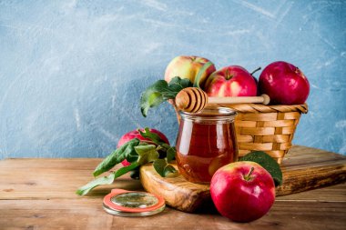Yahudi tatil Rosh Hashanah ya da elma Bayramı gün konseptiyle, kırmızı elma, elma yaprakları ve bal kavanozuna, açık mavi ve ahşap renkli kopya alanı