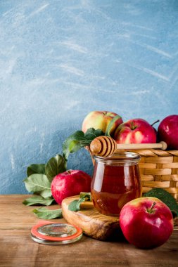Yahudi tatil Rosh Hashanah ya da elma Bayramı gün konseptiyle, kırmızı elma, elma yaprakları ve bal kavanozuna, açık mavi ve ahşap renkli kopya alanı