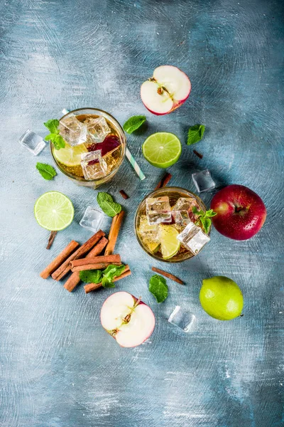 Spicy cinnamon apple iced tea or lemonade cocktail, summer refreshment drink, blue background copy space