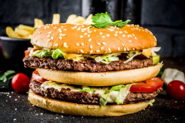 Çeşitli parti gıda, hamburger, patates kızartması, patates cipsi, salatalık turşusu, soğan, domates ve soğuk bira şişeleri, paslı siyah beton arka plan kopya alanı