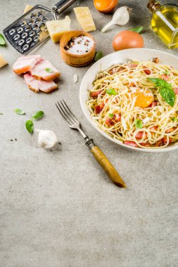 Geleneksel İtalyan Makarna, spagetti carbonara pastırma, krem sos, parmesan peyniri, yumurta sarısı ve taze fesleğen yaprakları gri taş arka plan kopya alanı