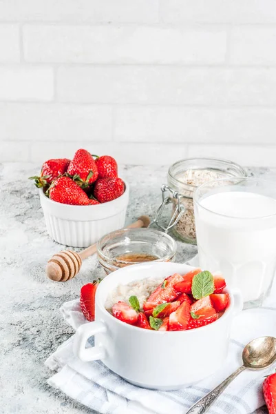 Sağlıklı yaz Kahvaltı, gece yulaf ezmesi taze çilek ve süt, gri taş arka plan