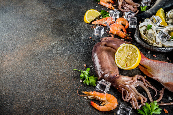 Fresh raw seafood squid shrimp oyster mussels fish with spices of herbs lemon on dark rusty background copy space top view