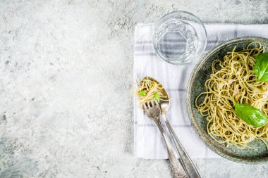 Spagetti makarna pesto ve taze fesleğen yaprakları, gri taş arka plan kopya alanı