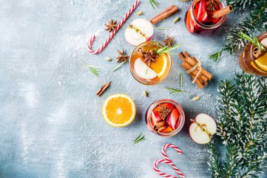 Geleneksel kış içecekler, beyaz ve kırmızı mulled şarap kokteyl ile beyaz ve kırmızı şarap, baharat, elma, portakal. Üzerinde mavi masa lambası,