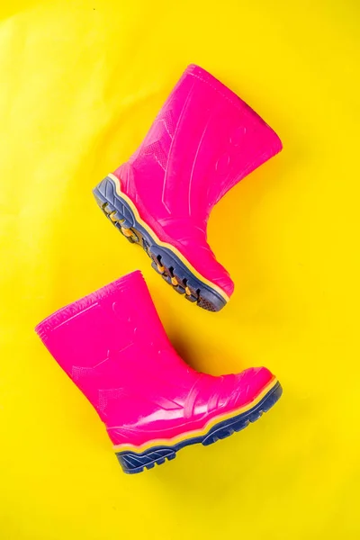 Autumn kids cloth concept, bright pink rubber boots for rain, top view