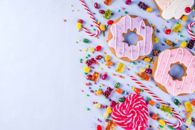 Tatlılar yaratıcı paralamak, lolipop, reçel, şeker, çerezleri çörek ve cupcakes, parlak sarı arka plana üstten görünüm kopya alanı ile tatlı kavramı